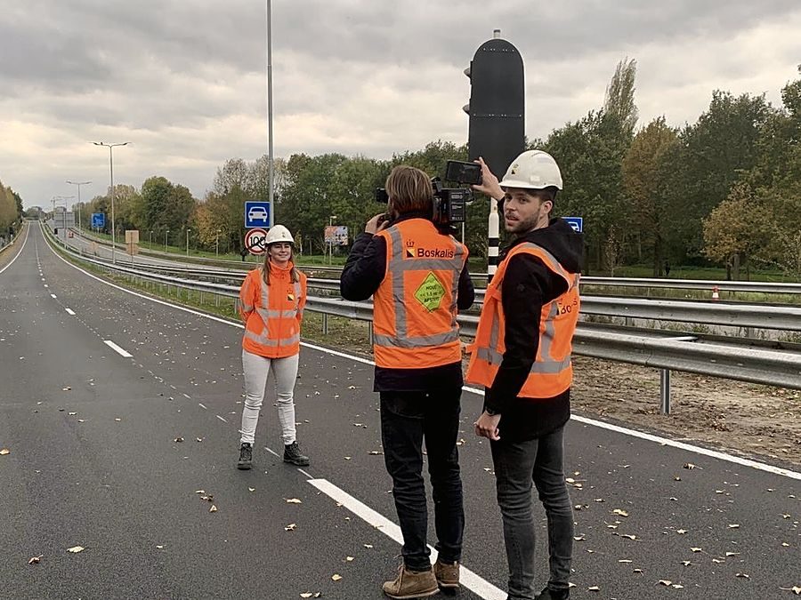 Een medewerker vertelt voor de camera op een afgesloten rijbaan